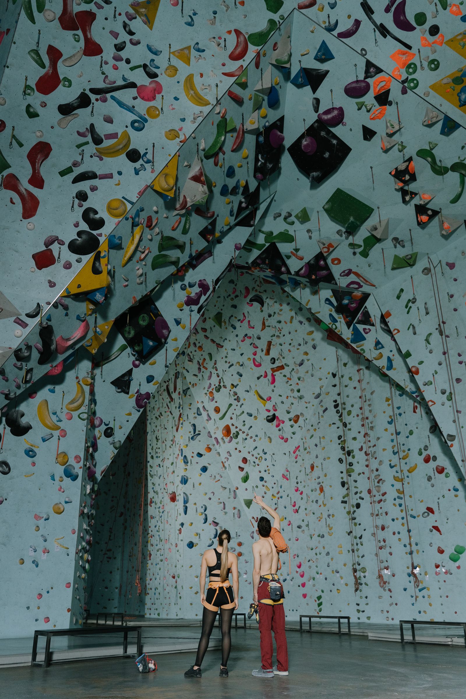 Two climbers studying routes in an indoor climbing gym